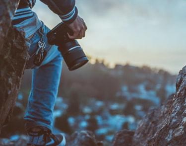 man standing in front of a lake holding a camera